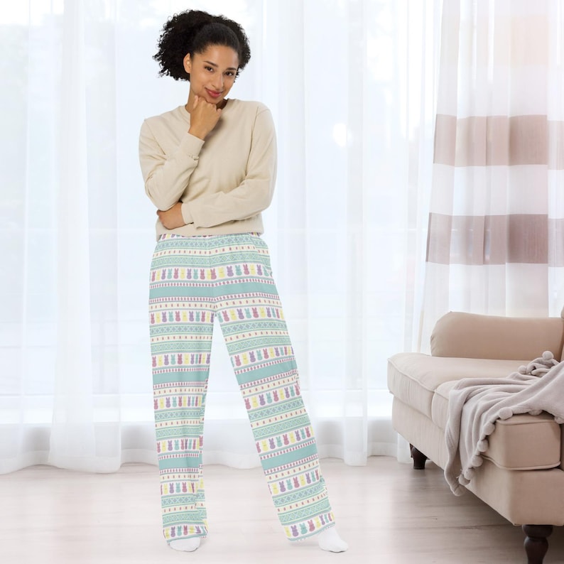 May include: A light beige long-sleeved top and pajama trousers. The trousers feature a light blue background with a repeating pattern of Easter bunnies in pastel colours. The trousers have a wide-leg design.