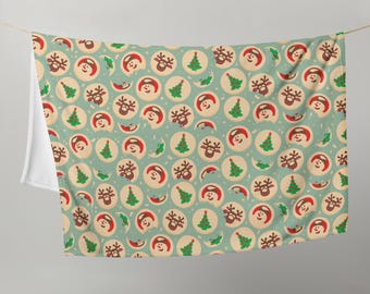 May include: A light blue throw blanket with a repeating pattern of Christmas cookies. The cookies feature a snowman, reindeer, and Christmas tree design. The blanket is hanging from a string.