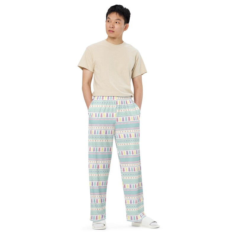 May include: Light blue pajama trousers with a repeating pattern of Easter bunnies in pastel colours. The trousers have a white waistband and a relaxed fit. The pajama trousers are made of a soft, comfortable material.