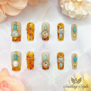 May include: Ten faux nail tips with a leopard print design. Each nail tip features a different design with turquoise and white stones, gold accents, and rhinestones.
