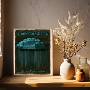 Framed poster on a console table with pampas grass on the left. The cyan headline and cloud above an umbrella formed of binary digits are visible in the top half of the print.