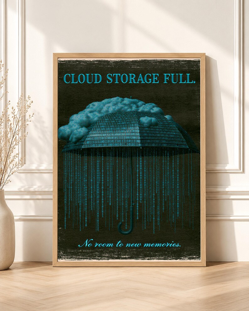 Close-up framed poster in a light wood frame leaning against a paneled wall. Top of artwork shows bright cyan serif headline 'CLOUD STORAGE FULL.' over a dark textured field and the top of a binary-code umbrella and cloud.