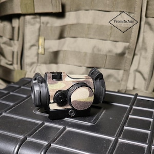 Op de afbeelding: Een camouflage-gepatroneerd rood puntvizier met zwarte accenten. Het vizier is gemonteerd op een zwarte kunststof behuizing.