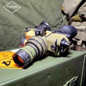 May include: Night vision device with a camouflage pattern, featuring black eyepieces and a lens with an orange hue. The device is labeled with the text "Promelechus Custom Workshop".