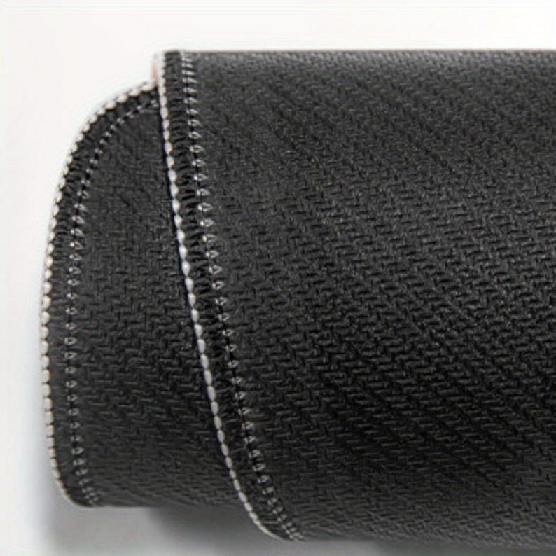 May include: Close-up of a black mouse pad with a textured surface and white stitching around the edges.