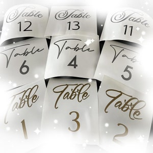 May include: White table number cards with black and gold lettering. The numbers range from 1 to 13.