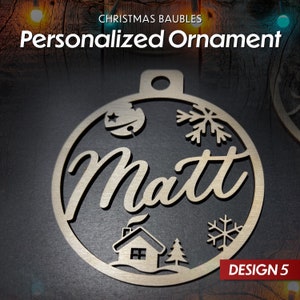 May include: A wooden Christmas bauble with a snowflake, a house, and a star design. The bauble is personalised with the name "Matt" and the text "DESIGN 5".