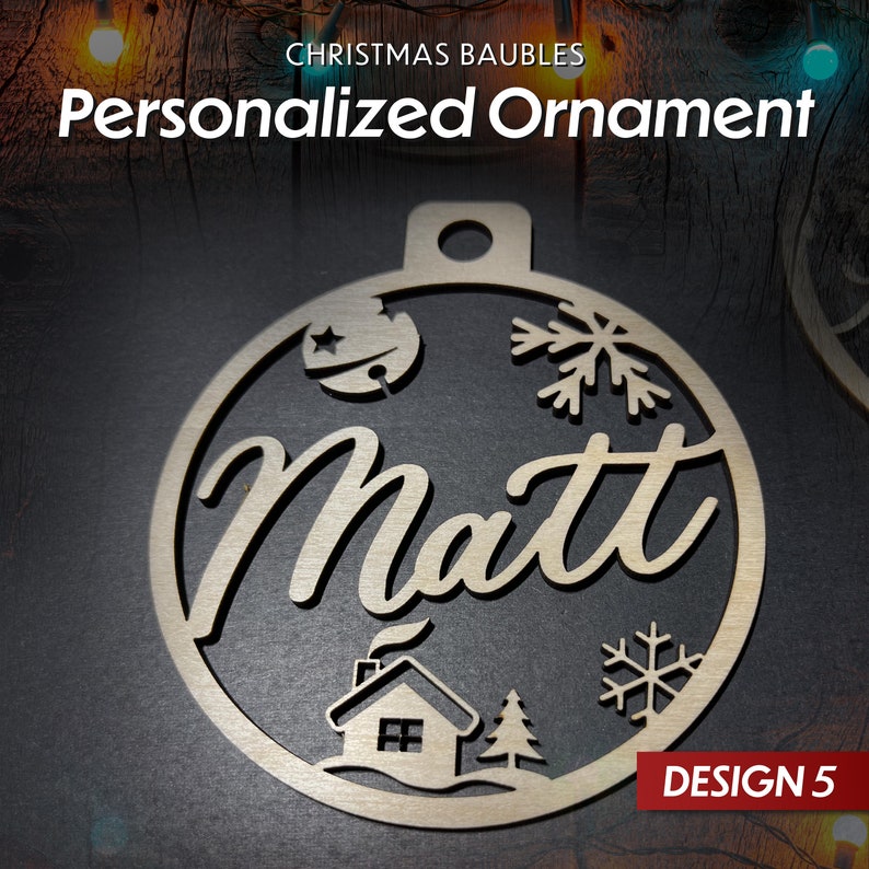 May include: A wooden Christmas bauble with a snowflake, a house, and a star design. The bauble is personalised with the name "Matt" and the text "DESIGN 5".