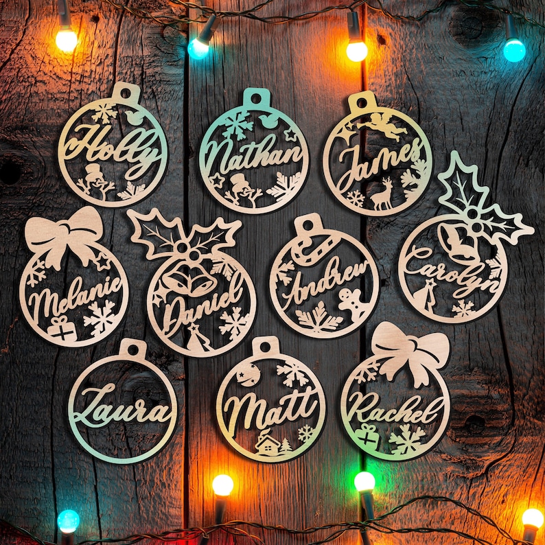 May include: Nine wooden Christmas baubles with names on them, including Holly, Nathan, James, Melanie, Daniel, Andrew, Carolyn, Laura, and Matt. The baubles are decorated with snowflakes and other wintery designs.
