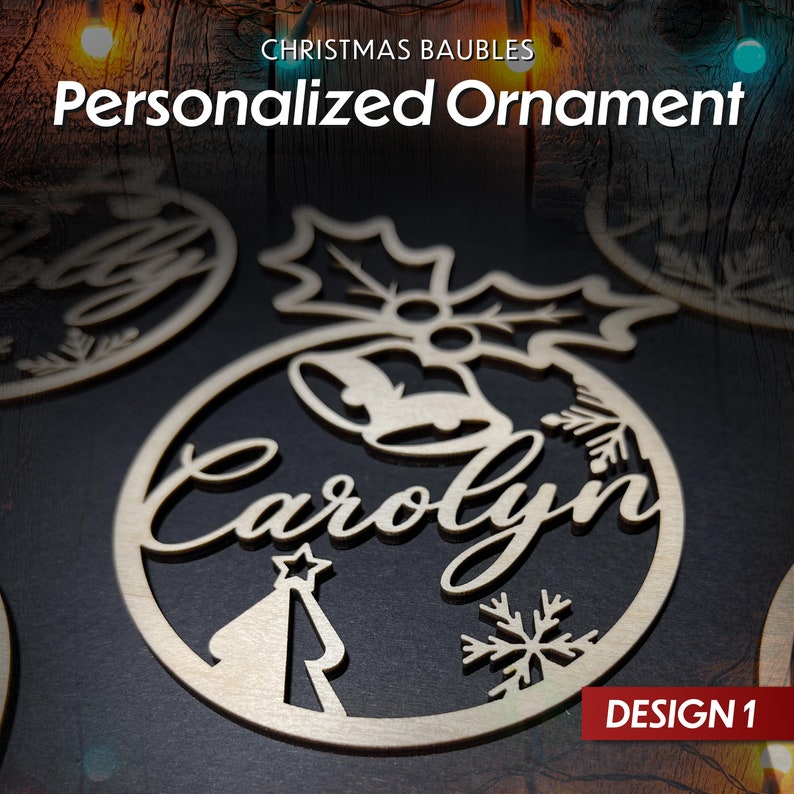 May include: A wooden Christmas bauble with a holly design, a bell, a snowflake, and a Christmas tree. The bauble is personalised with the name "Carolyn" and the text "DESIGN 1".