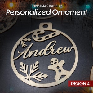 May include: A wooden Christmas bauble with a snowflake, candy cane, gingerbread man, and the name "Andrew" cut out. The bauble is round and has a brown background. The text "DESIGN 4" is visible in the bottom right corner.
