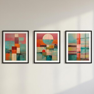 Puede incluir: Tres impresiones artísticas abstractas enmarcadas. Cada impresión presenta un diseño geométrico colorido con una mezcla de formas y colores, incluyendo turquesa, naranja, rosa y blanco. Los marcos son negros y el arte se exhibe en una pared blanca.