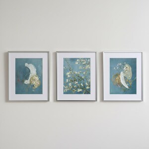 Puede incluir: Tres impresiones artísticas enmarcadas con marcos plateados. Las impresiones presentan diseños abstractos y una rama floral sobre un fondo verde azulado. La obra de arte añade elegancia.