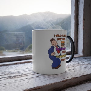 May include: White ceramic mug with a black handle. The mug features a cartoon character holding a hamburger and the text "I will gladly pay you Tuesday for a hamburger today."