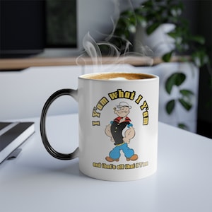 May include: White ceramic coffee mug with a black handle. The mug features a cartoon image of Popeye with the text "I yam what I yam and that's all that I yam".