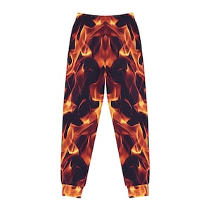 May include: Jogger trousers featuring a striking flame design in orange and yellow hues set against a dark backdrop. These trousers have a comfortable fit, with elasticated cuffs at the ankles and a matching waistband.
