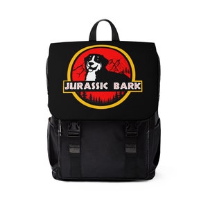May include: Black backpack with a red, yellow, and white Jurassic Park-inspired logo featuring a dog and the text "Jurassic Bark".