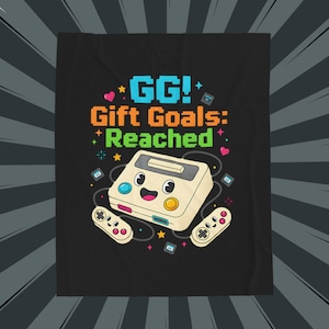 May include: Black t-shirt featuring a retro video game console with a smiling face and two controllers. The text "GG! Gift Goals: Reached" is displayed in pixelated font with colorful accents, including stars and hearts.