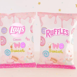 May include: Two bags of Lay's and Ruffles potato chips with a pink and white design. The bags feature the words "Two Sweet" with donuts, lollipops, and macarons. The bags have a pink border and a pink and white dripping design.