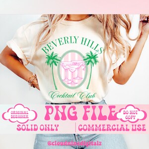 May include: A white t-shirt with a green and pink design that says "Beverly Hills Cocktail Club". The design features palm trees and martini glasses. The text "PNG FILE" is in pink with a retro font. The text "SOLID ONLY" and "COMMERCIAL USE" are in black. The text "ORIGINAL DESIGNER" and "DO NOT COPY" are in white and are in a cloud shape.