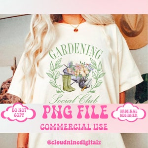 May include: A white t-shirt with a green wreath design that says "Gardening Social Club" and features a watercolor illustration of a wheelbarrow with flowers, gardening tools, and green rain boots. The text "PNG File Commercial Use" is in pink letters below the design.