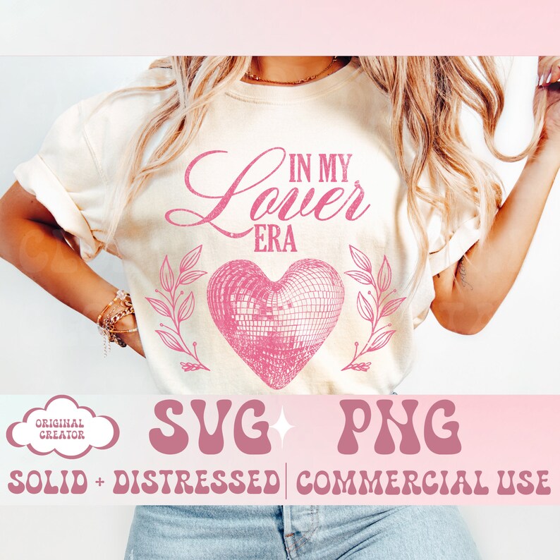 May include: Cream-colored t-shirt with the text "IN MY Lover ERA" in pink script above a pink disco ball heart design. The design is flanked by pink leafy branches. Below the design are the words "SVG PNG SOLID + DISTRESSED | COMMERCIAL USE".