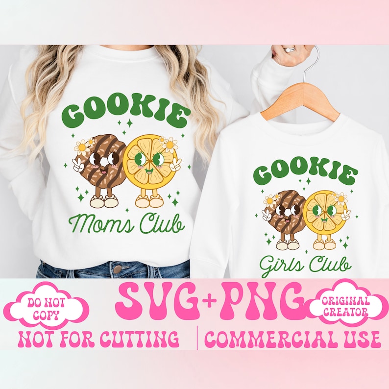 May include: Two white t-shirts with a graphic design of a cookie and a lemon slice with faces. The text on the shirts reads "Cookie Mom's Club" and "Cookie Girls Club".