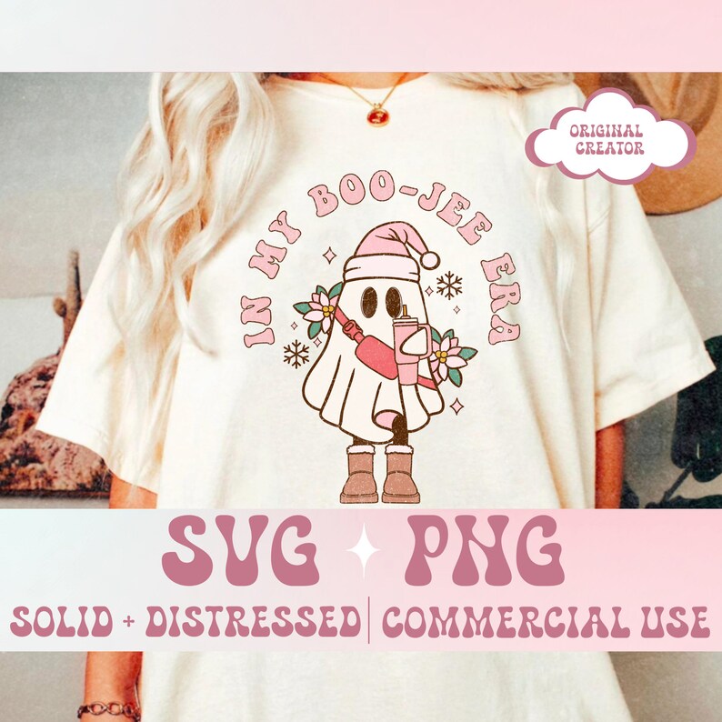 May include: Cream-colored t-shirt featuring a cartoon ghost wearing a pink Santa hat, holding a drink, and a fanny pack. The text "IN MY BOO-JEE ERA" is arched above the ghost. Below the ghost are the words "SVG + PNG" and "SOLID + DISTRESSED | COMMERCIAL USE".