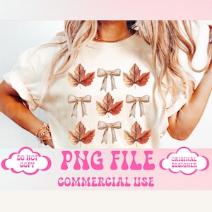 May include: A white t-shirt featuring a pattern of brown and orange maple leaves and brown bows. The text "PNG FILE COMMERCIAL USE" is printed in pink below the image. The words "DO NOT COPY" and "ORIGINAL DESIGNER" are printed in pink in speech bubbles on either side of the image.