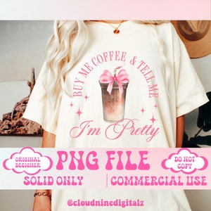 May include: A white t-shirt with a pink graphic design that says "Buy me coffee & tell me I'm pretty". The graphic features a cup of iced coffee with a pink bow. The shirt is for commercial use only.