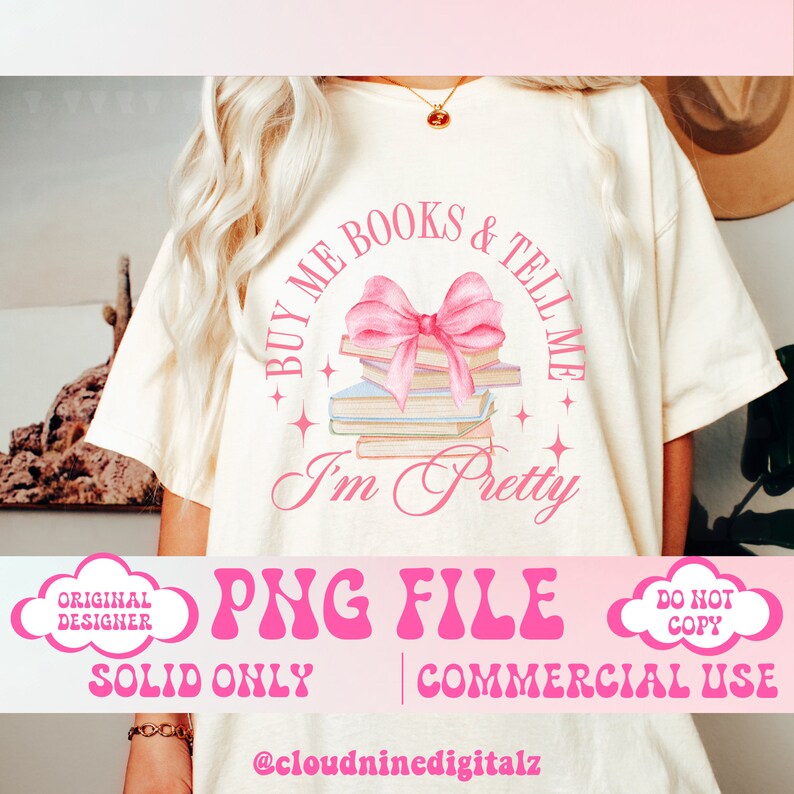May include: A pink and white graphic design on a white t-shirt with the text "Buy me books & tell me I'm pretty". The design features a stack of books with a pink bow on top.