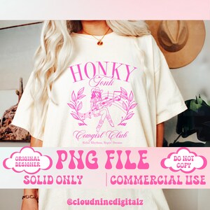 May include: A pink and white graphic design with the text "Honky Tonk Cowgirl Club Ridin' Rhythms, Ropin' Dreams" and a cartoon image of a cowgirl playing a guitar. The design is on a white t-shirt.