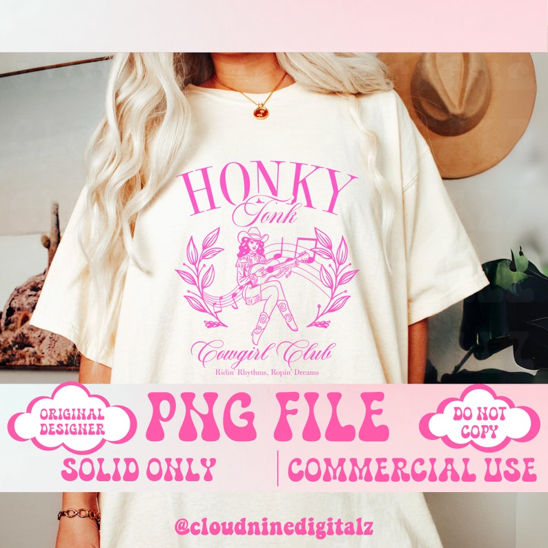 May include: A pink and white graphic design with the text "Honky Tonk Cowgirl Club Ridin' Rhythms, Ropin' Dreams" and a cartoon image of a cowgirl playing a guitar. The design is on a white t-shirt.