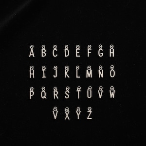 K&ouml;nnte beinhalten: Eine Sammlung von sechsundzwanzig einzelnen silberfarbenen Metall-Buchstabenanh&auml;ngern, die jeweils einen Gro&szlig;buchstaben von A bis Z zeigen. Jeder Buchstabenanh&auml;nger ist mit einem kleinen runden Biegering an der Oberseite versehen.