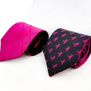 May include: Two neckties, one pink with a diagonal pattern and one black with a pink ribbon pattern.