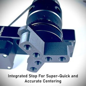 May include: A black camera accessory with a three-pronged stop for quick and accurate centering. The stop is made of a textured black plastic and has a series of small holes.