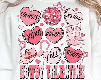 May include: White sweatshirt with a pink and white graphic design featuring hearts, cowboy boots, a horseshoe, a cowboy hat, and the text "Howdy Valentine", "Cowboys", "Y'all", "Howdy", "Yeehaw", "Boots", and "XOXO".