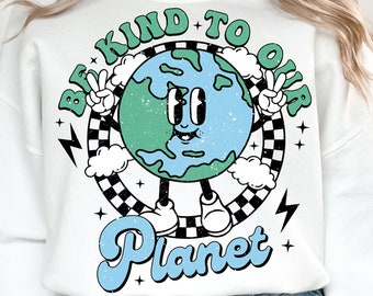 Op de afbeelding: Wit sweatshirt met een afbeelding van een cartoon-aarde met een glimlach en de tekst "Be Kind To Our Planet" in een retro-stijl.