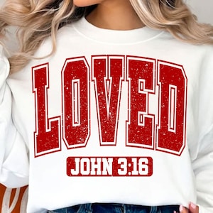 May include: White sweatshirt with a red distressed graphic that says "LOVED" with "JOHN 3:16" underneath.