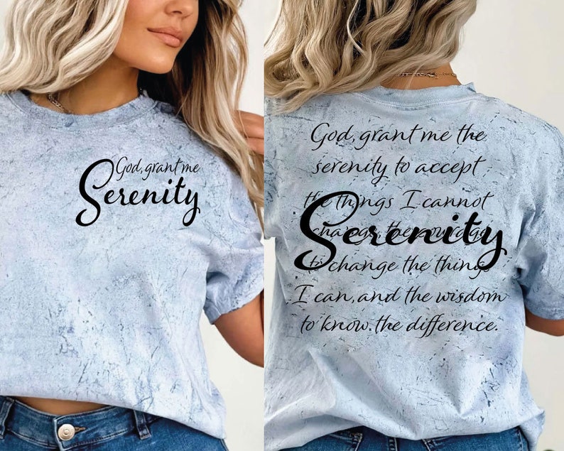 May include: A light blue t-shirt with a distressed, marbled effect. The shirt features a black graphic with the text "God, grant me Serenity" on the front and the text "God, grant me the serenity to accept the things I cannot change, Serenity to change the things I can, and the wisdom to know the difference." on the back.