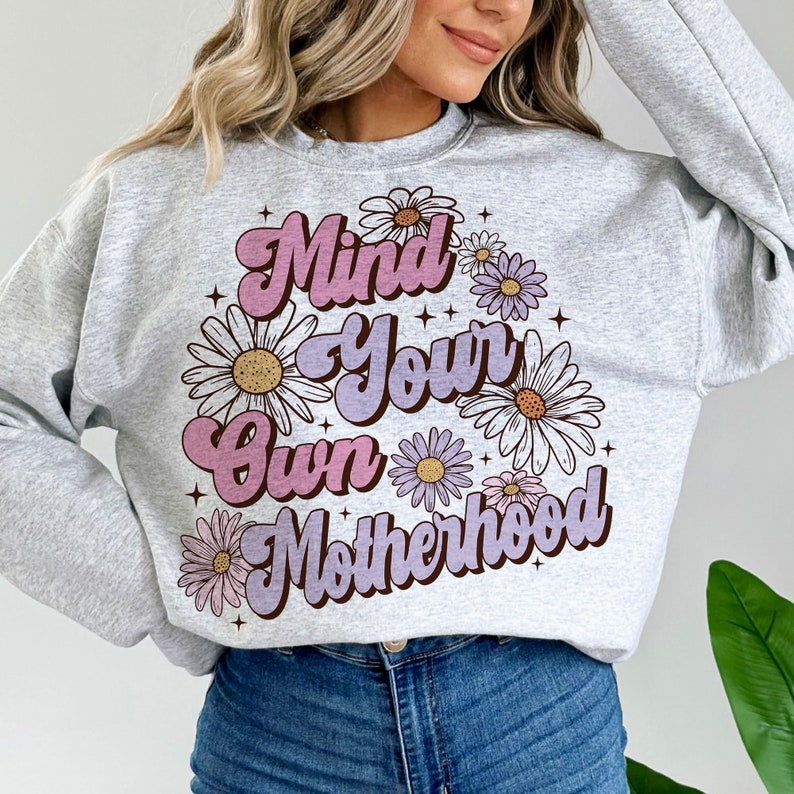 May include: Gray sweatshirt with a pink and purple graphic that says "Mind Your Own Motherhood" surrounded by white and purple daisies.