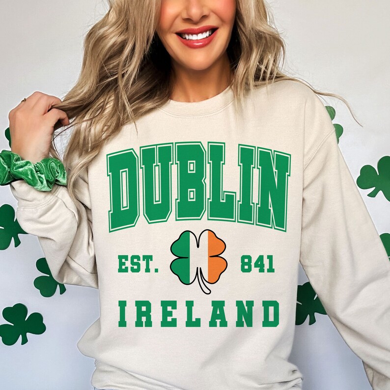 May include: A cream colored sweatshirt with the text "DUBLIN EST. 841 IRELAND" in green letters. A green shamrock with an orange center is between the words "EST." and "841".