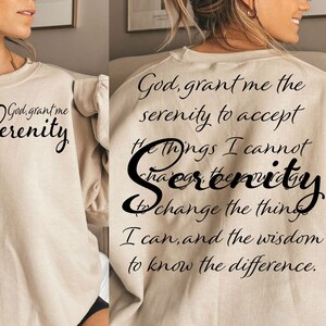May include: A beige sweatshirt with the text "God, grant me the serenity to accept the things I cannot change, serenity to change the things I can, and the wisdom to know the difference." printed on the back.