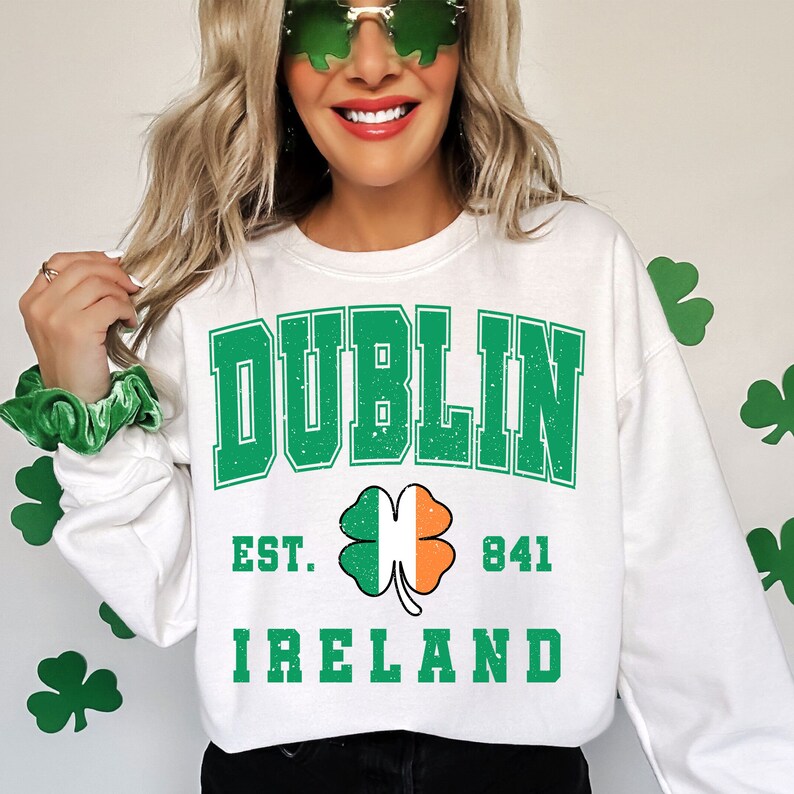 May include: White sweatshirt with green text that reads "DUBLIN EST. 841 IRELAND". A green shamrock with an orange and white center is between the words "EST." and "841".