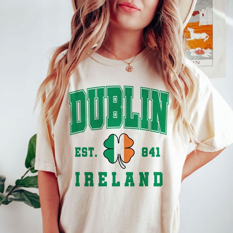 May include: A cream colored t-shirt with the text "DUBLIN EST. 841 IRELAND" in green letters. A green shamrock with an orange and white center is between the words "EST." and "841".