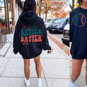 May include: Black hooded sweatshirt with the text "Hey Batter Batter Swing" and a baseball graphic in green, red, and white.