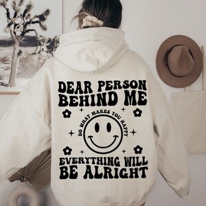 K&ouml;nnte beinhalten: Ein wei&szlig;er Hoodie mit einem schwarzen Aufdruck, der "Liebe Person hinter mir tu, was dich gl&uuml;cklich macht alles wird gut" mit einem Smiley in der Mitte sagt.