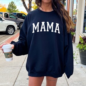 May include: Black sweatshirt with white text that reads "MAMA" in a collegiate font.