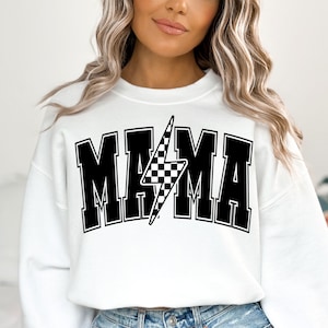 Puede incluir: Sudadera blanca con texto negro que dice "MAMA" con un rayo negro y blanco a cuadros en el medio.