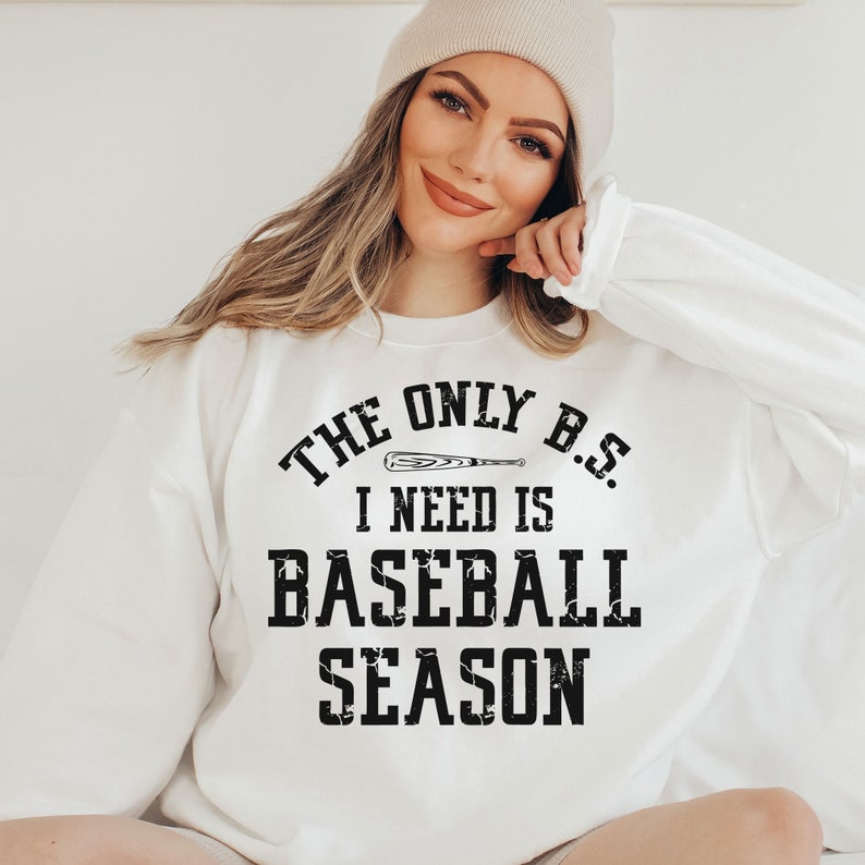 May include: White sweatshirt with black text that reads "The only B.S. I need is baseball season" with a baseball bat graphic.